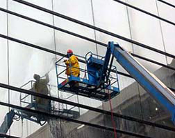 Workers on a lift performing quality checks on a glass wall installation.
